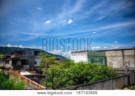 View of houses, mountains and building of brick slums in Bangu neighborhood, where the prison, the Penitentiary Complex of Gericino and Bangu dump are located, the West Zone of Rio de Janeiro, Brazil
