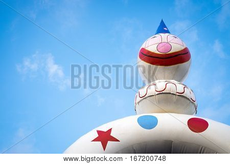 White clown jumping castle against blue sky background with white clouds