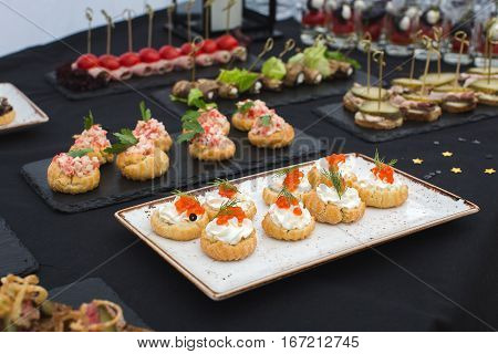 Delicious different snacks with red cavior close-up on the black table in the restaurant during celebration
