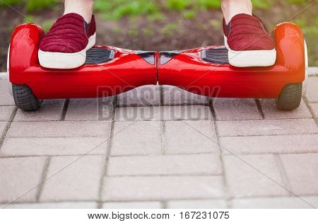 Cllose up on feet of a gir in marsala shoes riding on a modern red electric mini segway or hover board scooter. Trending new transportation technology that is so much fun and easy to ride and produces no air pollution to the atmosphere.