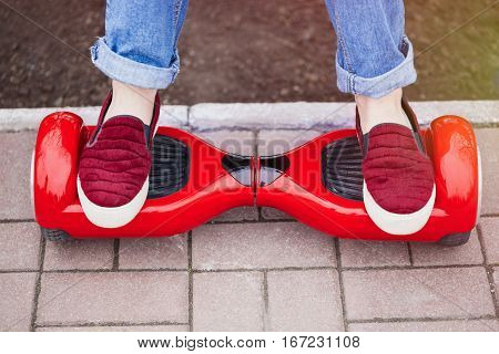 Feet of a gir in marsala shoes riding on modern red electric mini segway or hover board scooter. Trending new transportation technology that is so much fun and easy to ride and produces no air pollution to the atmosphere. Focus on the device
