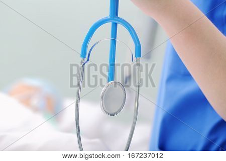 Stethoscope in hand of doctor at the bedside.