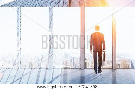 Rear view of a businessman with a suitcase standing in an office with panoramic windows. 3d rendering. Mock up. Toned image. Double exposure.