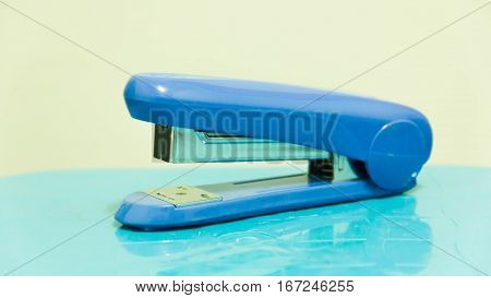 Blue stapler and piles of copper office staples on wooden office, closeup, top view