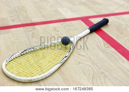 squash racket and ball on the wooden floor. Racquetball equipment on the court next to a red line. Photo with selective focus. Squash time