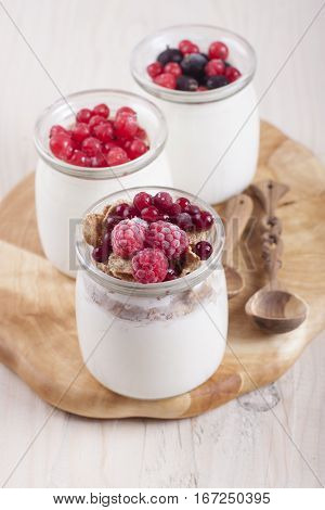 Homemade yogurt with frozen berries red currants black currants raspberries and cranberries in three banks