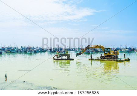 MIRISSA SRI LANKA - DECEMBER 3 2016: The amphibious excavator pushes the cargo trailer with its bucket to the shore on December 3 in Mirissa.