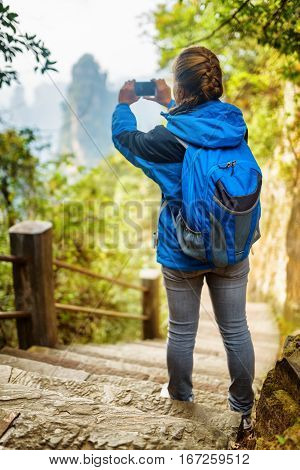 Young Female Tourist With Blue Backpack Taking Photo