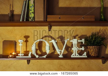 Diy love word made of paper standing on a bookshelf.