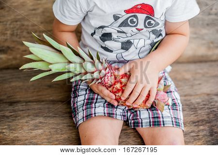 Organic Pink Pineapple In Hands On The Old Wooden Background