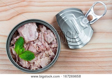 canned tuna on wood table / Canned albacore pink meat tuna packed in water