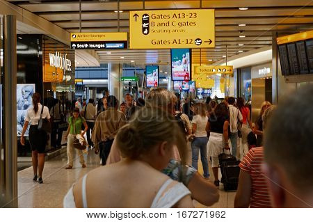 London, UK, 03 Jul. 2009: Many passengers walking toward A13-23 Gates in Heathrow Airport. Different direction and AD banners about.