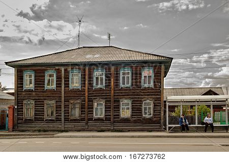 Yalutorovsk, Russia - May 27, 2006: Women wait for bus on stop near old house on Revolution street 55