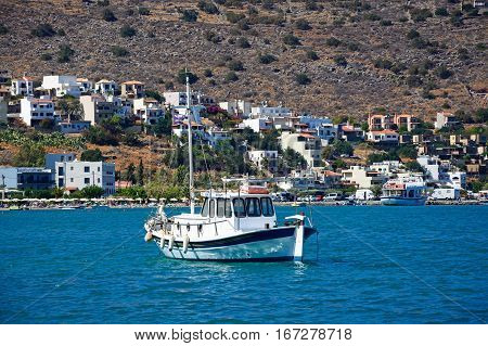 ELOUNDA, CRETE - SEPTEMBER 17, 2016 - Small yacht moored in the bay with buildings on the coastline to the rear Elounda Crete Greece Europe, September 17, 2016.