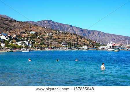 ELOUNDA, CRETE - SEPTEMBER 17, 2016 - View along the beach and coastline with tourists relaxing in the sunshine Elounda Crete Greece Europe, September 17, 2016.