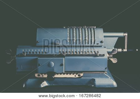Old calculating machine isolated on black background
