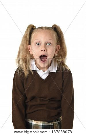 young beautiful and sweet schoolgirl in pigtails and school uniform looking amazed shocked and surprised in female child face expression isolated on white background