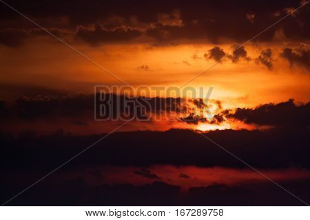 Dramatic sunset with dark sky and sun covered with clouds