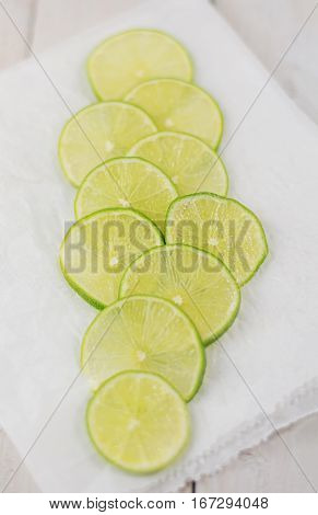 Cut slices of lime on white paper.
