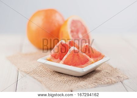 Sliced grapefruit on burlap fabric of whole and half in the background.