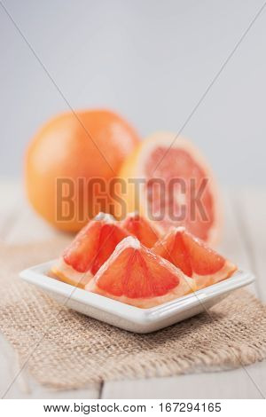 Sliced grapefruit on burlap fabric of whole and half in the background.