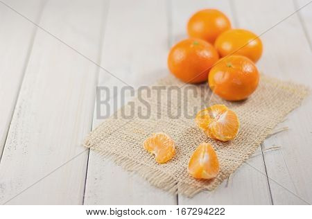Group of tangerines in the background and peeled mandarin in the foreground.