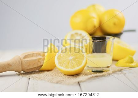 A glass of squeezed lemon juice and lemons around.