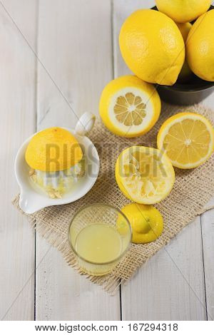 A glass of squeezed lemon juice and lemons around.
