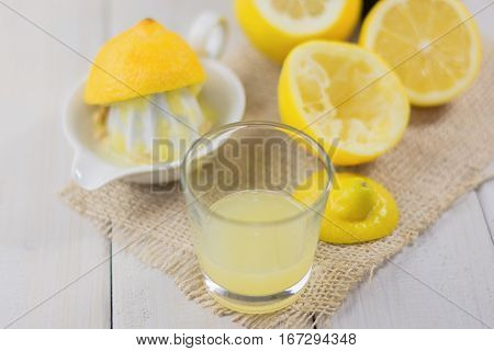 A glass of squeezed lemon juice and lemons around.