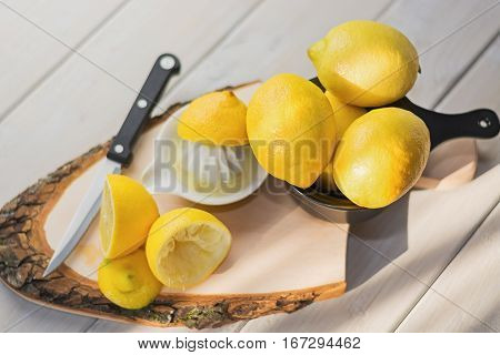 Juicer for lemon on a wooden plank and cut and whole lemons around.