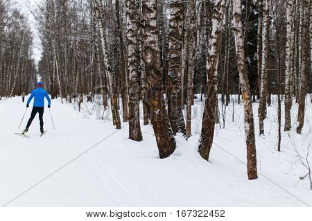 Man skiing on snowy road in woods during day