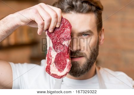 Close-up portrait of a handsome man with raw meat hiding his face