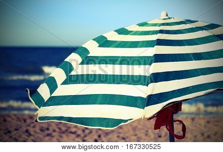 beach with sun umbrella with stripes and an antique effect