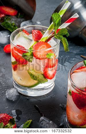 Summer refreshing mojito cocktail with strawberry mint and lime on a dark gray stone (concrete) table with shaker for whipping drinks