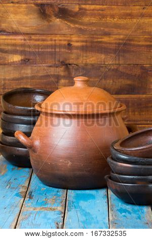 Clay dishes - plates and pot on wooden blue background