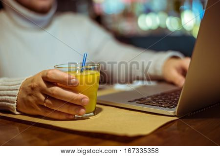 man drinks juse while working on laptop in cafe