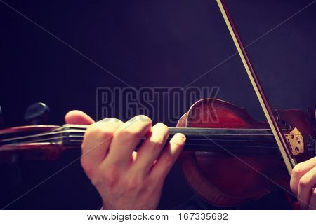 Music passion hobby concept. Close up young man man dressed elegantly playing on wooden violin. Studio shot on dark background