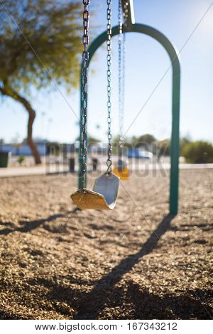 Play park kid's swings in a row. Depth of field view and close up of first swing/harness.