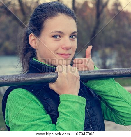 Young athlete giving thumbs up while doing pullups. Outdoor fintess.