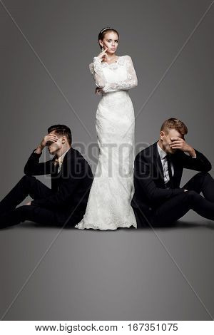 Two handsome men in suits and beautiful woman in white bridal dress. Studio, trendy, strict look