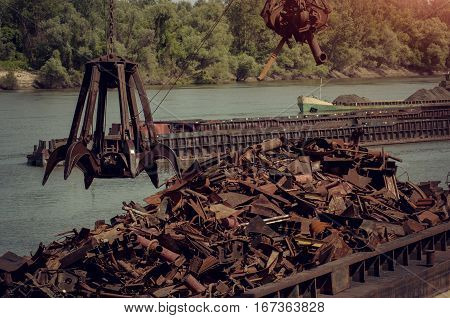 Metals recycling on a river bank with freighter in a background