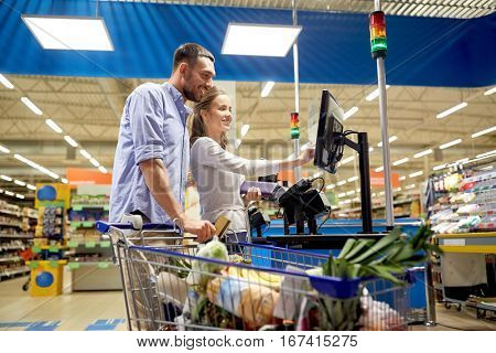 shopping, sale, payment, consumerism and people concept - happy couple with credit card buying food at grocery store or supermarket self-service cash register