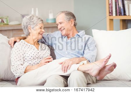 Happy senior couple sitting on sofa in living room at home