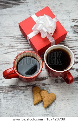 two red coffee cup, hearts cokies and gift box on wooden surface. Valentines day concept.