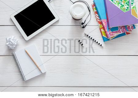 Student table background. Modern white office desk with tablet, books and other supplies with coffee take away cup. Blank open diary with copy space for text. Top view, flat lay.