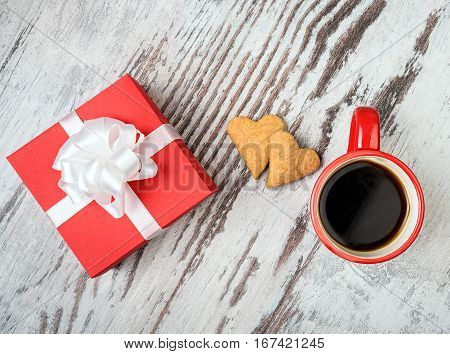 two red coffee cup, hearts cokies and gift box on wooden surface. Valentines day concept.