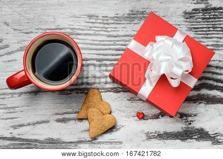 two red coffee cup, hearts cokies and gift box on wooden surface. Valentines day concept.