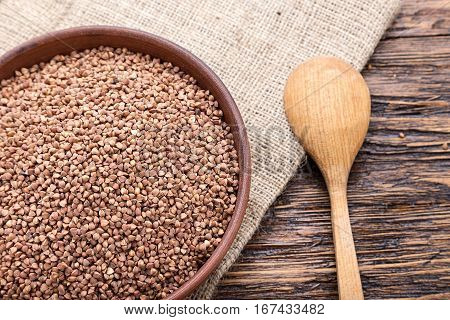 standing on a wooden background earthenware dish with raw buckwheat