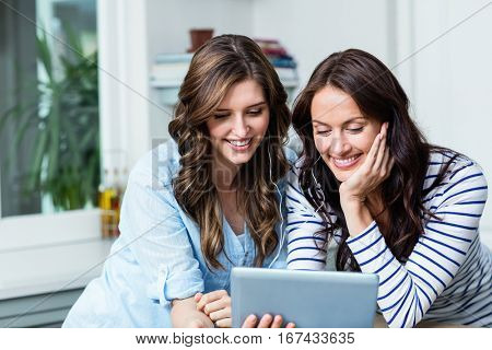 Smiling friends watching video on digital tablet at home