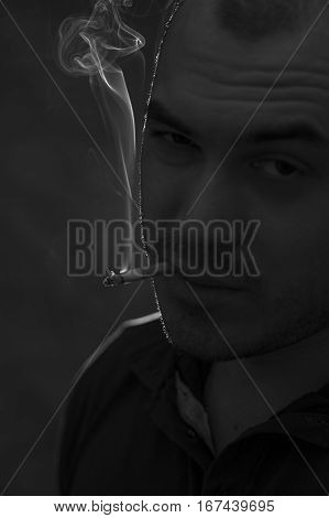 Portrait of young depressed man with cigarette. Bad habits concept. Black and white image